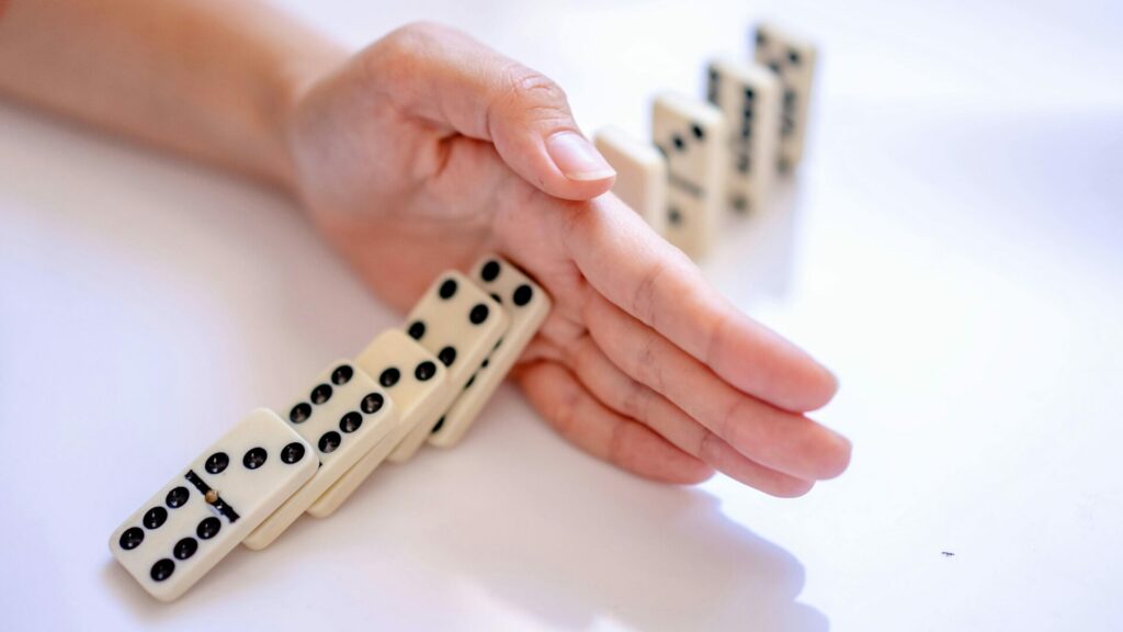 Main stoppant la chute de dominos, illustrant l’arrêt du tabac avec LaserAddict qui met fin à l’effet domino de la dégradation de la santé causée par la cigarette.