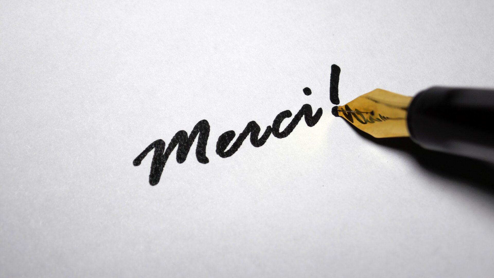 Stylo plume écrivant le mot « merci », symbole de gratitude et d’engagement humain chez LaserAddict