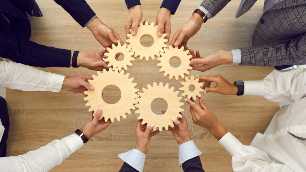 Équipe LaserAddict tenant des engrenages symbolisant le travail d’équipe, la franchise et l’accompagnement entrepreneurial dans le bien-être