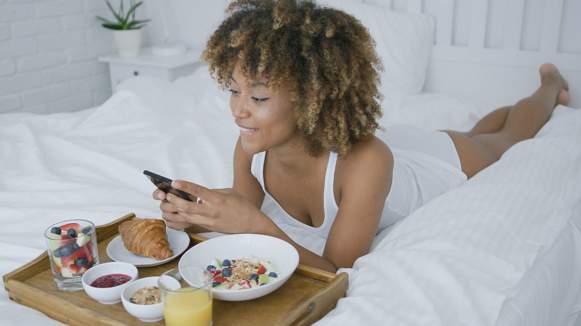 Femme au réveil dans son lit savourant un petit-déjeuner équilibré, symbolisant l’importance du sommeil et de la nutrition après un sevrage – LaserAddict