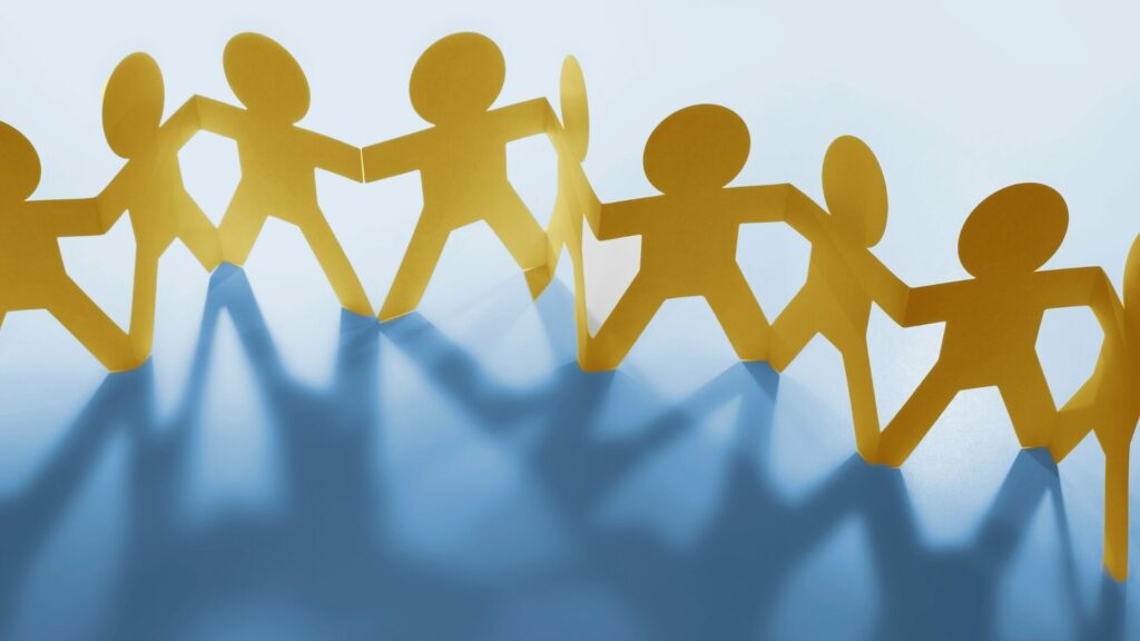 Bonhommes de papier se tenant par la main en farandole, symbolisant la force du collectif et l’accompagnement du réseau LaserAddict auprès de chaque centre.