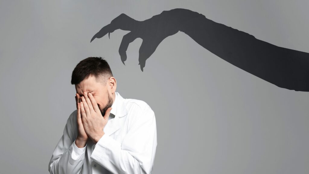 Homme cachant ses yeux avec l’ombre de griffes effrayantes symbolisant la peur d’arrêter de fumer – accompagnement sevrage tabagique LaserAddict